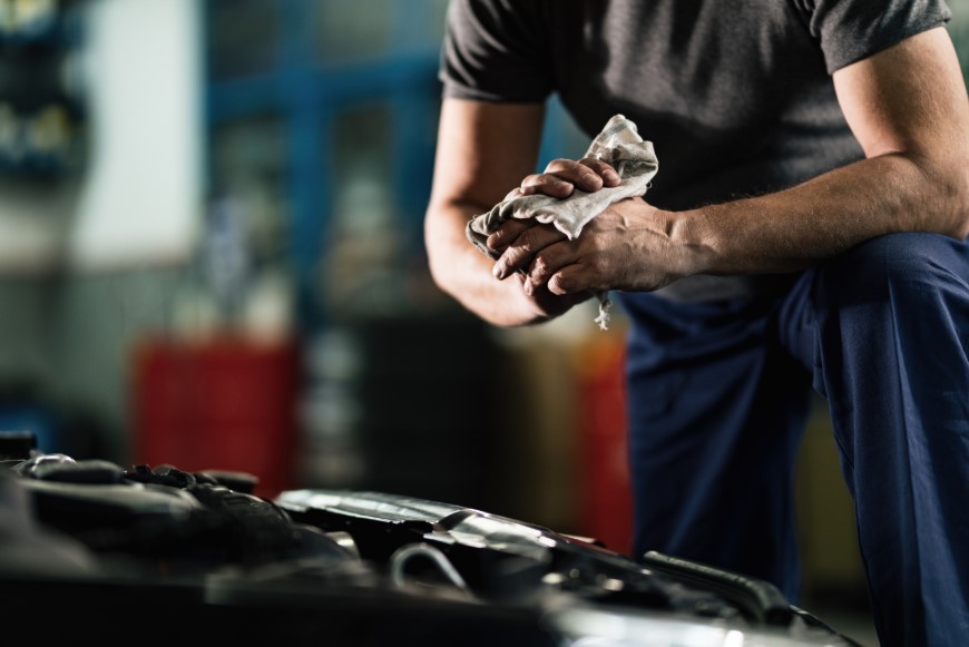 Mechanic cleaning hands after handling engine oil in a workshop.